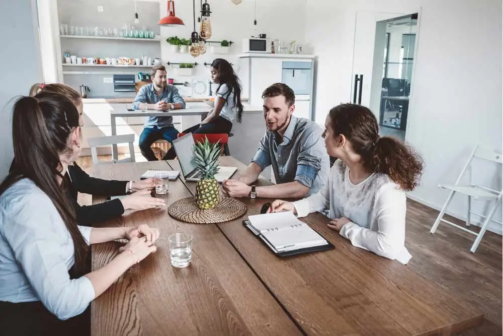Ett städat lunchrum på ett kontor med 6 personer som har möte.
